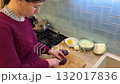A housewife cuts beet on a wooden soup board in the kitchen. 132017836