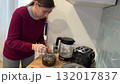 Young woman pouring tea with honey from teapot into cup in kitchen 132017837