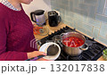 Focused and calm, the woman cooks vegetable borscht, filling her cozy kitchen with the scent of simmering vegetables and Eastern European spices. 132017838