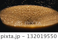 Close-up photograph of golden glittering sand leaking out of an hourglass. 132019550