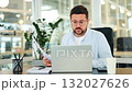 Concentrated Businessman Reviewing Documents on Laptop in Office 132027626
