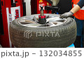 Car wheel positioned on a tire changing machine before removing the tire from the rim. Seasonal tire replacement process at an auto service during winter preparation. 132034855