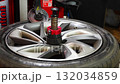 Tire changing machine removing the rubber tire from the rim using a rotating metal arm. Essential step in seasonal wheel replacement at a professional auto workshop. 132034859