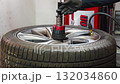Inflating a car tire on a tire changing machine during seasonal wheel replacement. Critical step for proper pressure and road safety before winter driving. 132034860
