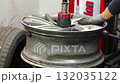 Mechanic lubricates car tire after removing it from the wheel rim. Seasonal tire change preparation during winterization service in an auto workshop. 132035122