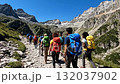 A group of people walking up a mountain trail with backpacks 132037902