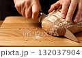 A person cutting a loaf of bread with a knife 132037904
