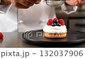 A person sprinkling powdered sugar on top of a dessert 132037906