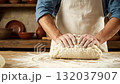 A person kneading dough on a table with flour 132037907
