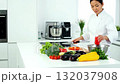 A woman in a kitchen preparing food on a cutting board 132037908