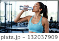 A woman in a blue sports bra holding a bottle of water 132037909