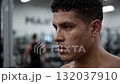 A shirtless man in a gym with a barbell in his hand 132037910