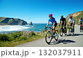 A group of people riding bikes down a road next to the ocean 132037911