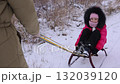 Mother pulls sled with little girl while father walks behind on winter day 132039120