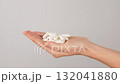 Hand holding a pile of white capsules on a neutral background with copy space. Concept of dietary supplements, vitamins and healthcare pills. 132041880