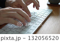 Hands typing on a white keyboard at a wooden desk. Image of programming or business 132056520