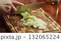 Fresh green onions, parsley, and dill being finely chopped by a chef on a wooden cutting board over a rustic wooden table. Macro 4K video showing green herbs preparation for a healthy meal. 132065224