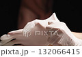 A Doctor Puts on White Gloves for Examination with a Naked Man Out of Focus in the Background. 132066415