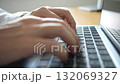 A scene of a person wearing a white shirt typing on a laptop keyboard at a natural wooden desk 132069327