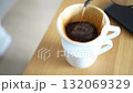 A scene of hand-dripping coffee on a wooden table. A white mug and a white dripper are used. 132069329