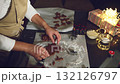 A woman bakes delicious gingerbread cookies during the Christmas holidays, surrounded by warm fairy lights and festive decor. Preparing homemade treats brings joy and tradition to the season. 132126797