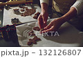A person carefully places freshly cut gingerbread cookies on parchment paper, preparing for baking. Captures the festive spirit of holiday traditions and homemade treats. 132126807