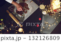 Overhead view of hands preparing gingerbread cookies for the festive season. Enjoy the warmth and tradition of holiday baking, surrounded by twinkling lights and cozy candles. 132126809