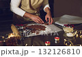 Hands prepare gingerbread dough with festive cookie cutters amidst warm string lights and candles, capturing the joyful spirit of holiday baking and Christmas tradition. 132126810