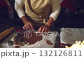 Close-up of hands cutting out festive gingerbread cookies from dough with cookie cutters. Perfect for holiday and Christmas baking content, celebrating homemade treats and sweet traditions. 132126811