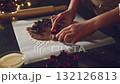 Close-up shot of hands using Christmas cookie cutters to shape gingerbread dough on parchment paper. This festive scene captures the joy of holiday baking and homemade treats. 132126813