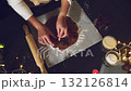 Overhead view of a woman's hands cutting gingerbread dough with festive cookie cutters, preparing delicious Christmas cookies in a warm, decorated home kitchen. Perfect for holiday season content and 132126814