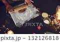 Enjoy the festive spirit as hands carefully roll out gingerbread dough on a dark table, ready for baking delicious Christmas cookies. Surrounded by warm holiday lights and cozy candles, it's perfect 132126818