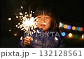 A happy young asian girl holds a lit sparkler at night. Celebrating a holiday with fireworks and drawing a heart shape with light. Childhood joy and wonder 132128561