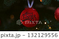 Festive Red Christmas Ornament on Tree with Merry Christmas Text 132129556