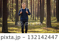 Young male hiker with backpack walks through beautiful sunlit pine forest during his adventure 132142447