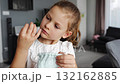Little girl placing her baby tooth into a small pouch for the tooth fairy. Capturing a tender childhood ritual filled with imagination and meaning. 132162885
