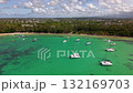 Aerial travel footage over Pereybere Beach Mauritius showing clear lagoon sandbanks moored yachts tropical shoreline and distant Moka mountains 132169703