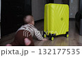 Baby crawling towards a yellow suitcase 132177535