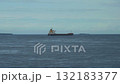 A bulk cargo carrier ship travels on a calm sea, cloudy sky 132183377