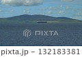 A merchant ship travels on a calm sea near the coast of Orkney 132183381
