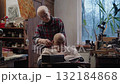 An elderly old man on a wheelchair receives a haircut from his wife at home with a trimmer 132184868