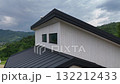 Abstract view of a modern house roofline and white siding contrasting with the lush green valley and rolling hills 132212433