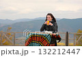 Woman enjoying orange juice at a mountain cafe table with a stunning view of the autumnal Carpathian ranges 132212447
