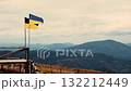 Ukrainian flag fluttering proudly on a mountain top overlooking the vast Carpathian ranges, epic landscape 132212449