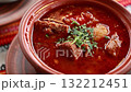 Authentic Ukrainian borscht soup served in a traditional clay bowl, rich red color and chopped parsley 132212451