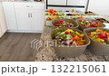 Plastic and ceramic bowls containing freshly chopped vegetables such as red onions, carrots, and bell peppers sit on a granite countertop. The arrangement displays a rainbow of natural colors. 132215061