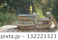 A stack of hardcover books on a wooden table in the forest 132221321