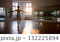 Dancer Practicing Graceful Movements in Studio at Sunset, Capturing the Beauty and Artistry of Ballet in a Warmly Lit Environment. 132225894