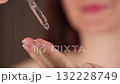 Serum Macro shot. Woman holding a serum dropper. Extreme close-up of drops of facial serum falling from the pipette. Skincare and beauty routine concept. Slow motion. Selective focus.  132228749