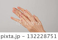 Female hands care. Woman gently massaging her hands moisturizes the skin using nourishing cream against a neutral background. Relaxation, Self-care, Beauty and Skincare concept.  132228751